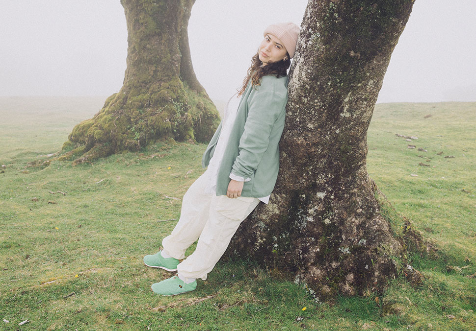 A person, leaning against a tree, wearing Teva 'ReEmber' shoes.