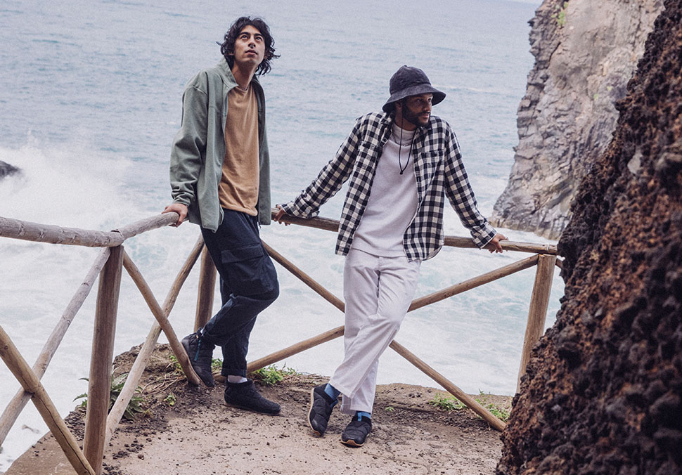 Two people, standing by the sea, wearing Teva 'ReEmber' shoes.