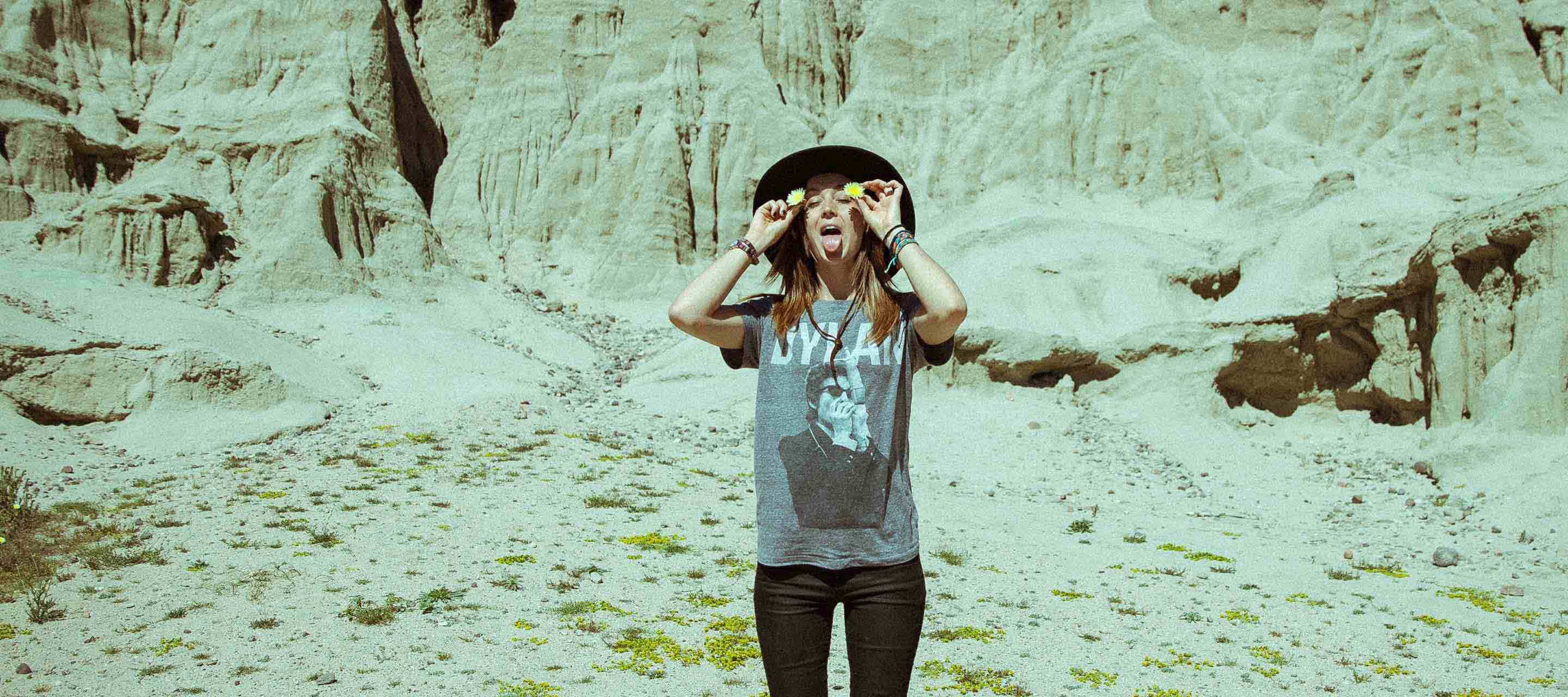 Kylie standing playfully in desert, holding flowers by her ears.