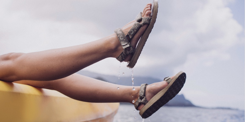 Close up of a person's legs, hanging in the air, wearing Teva sandals. 