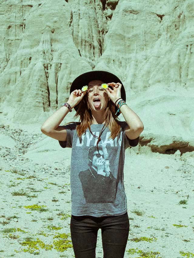 Kylie standing playfully in desert, holding flowers by her ears.