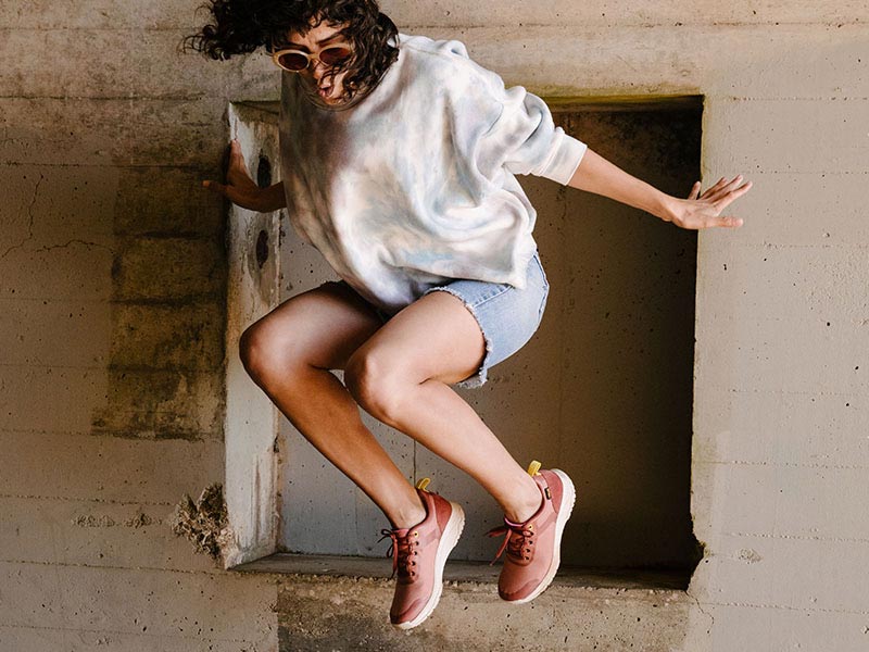 Woman jumping and in mid-air, while wearing Tevas.