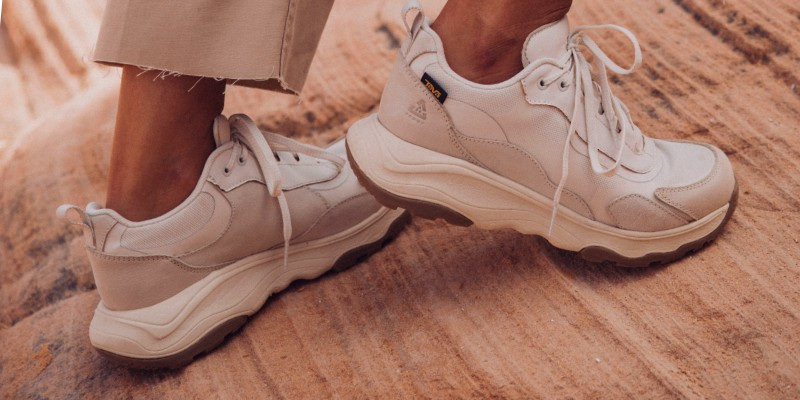 Close up of a person's feet wearing Teva boots while walking over a rocky ground.