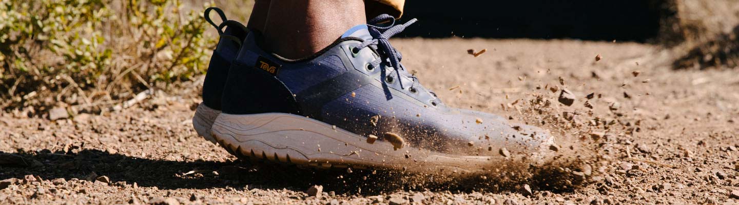 Mens Shoes Close up of mans feet, wearing Teva Shoes, jumping on a trail.