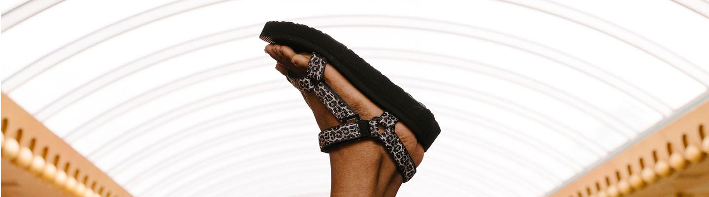 Close up of a woman's feet up in the air, wearing Teva sandals.