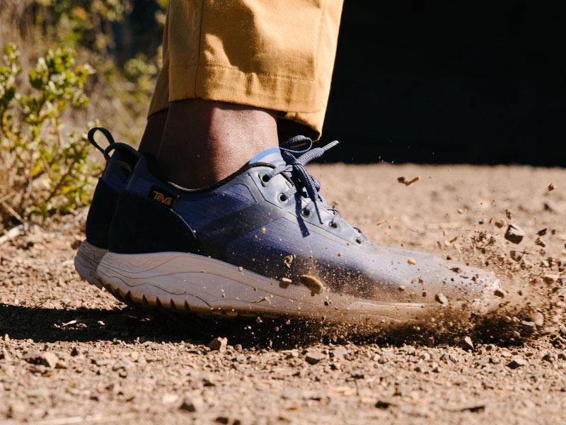 Mens Shoes Close up of mans feet, wearing Teva Shoes, jumping on a trail.