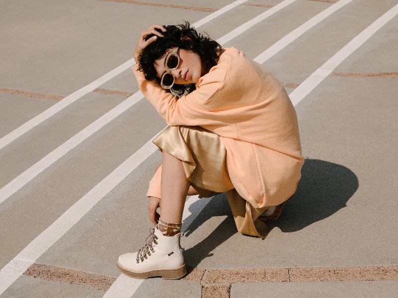 Woman sitting on some stairs, wearing stylish Teva boots.