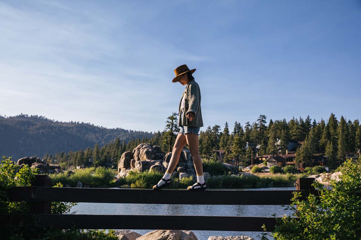 A woman walking on a fence with a river in the background.